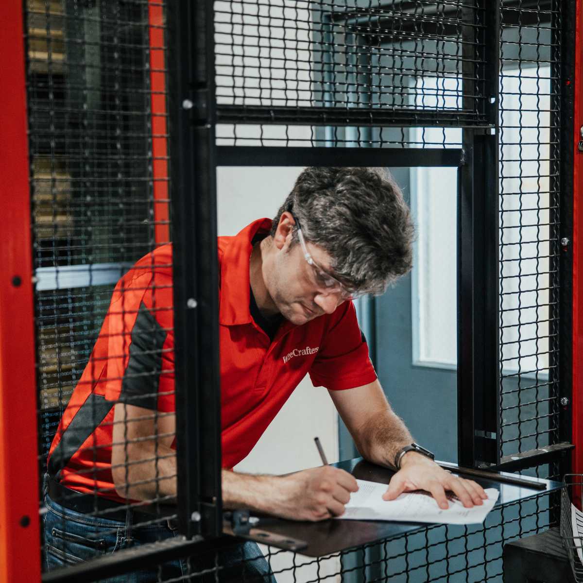 person in red shirt writing on surface in driver cage window