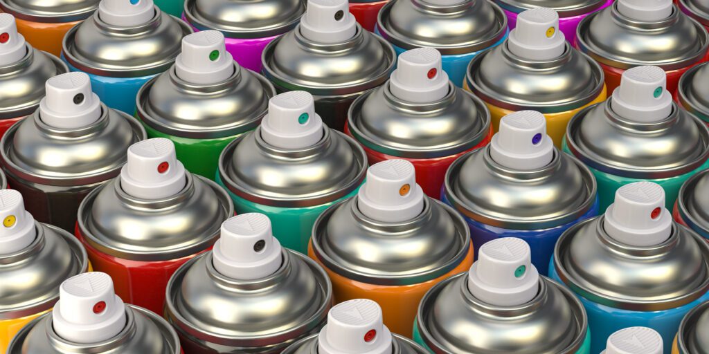 Rows of colorful graffity spray paint cans or bottles of aerosol aerosol paint cans